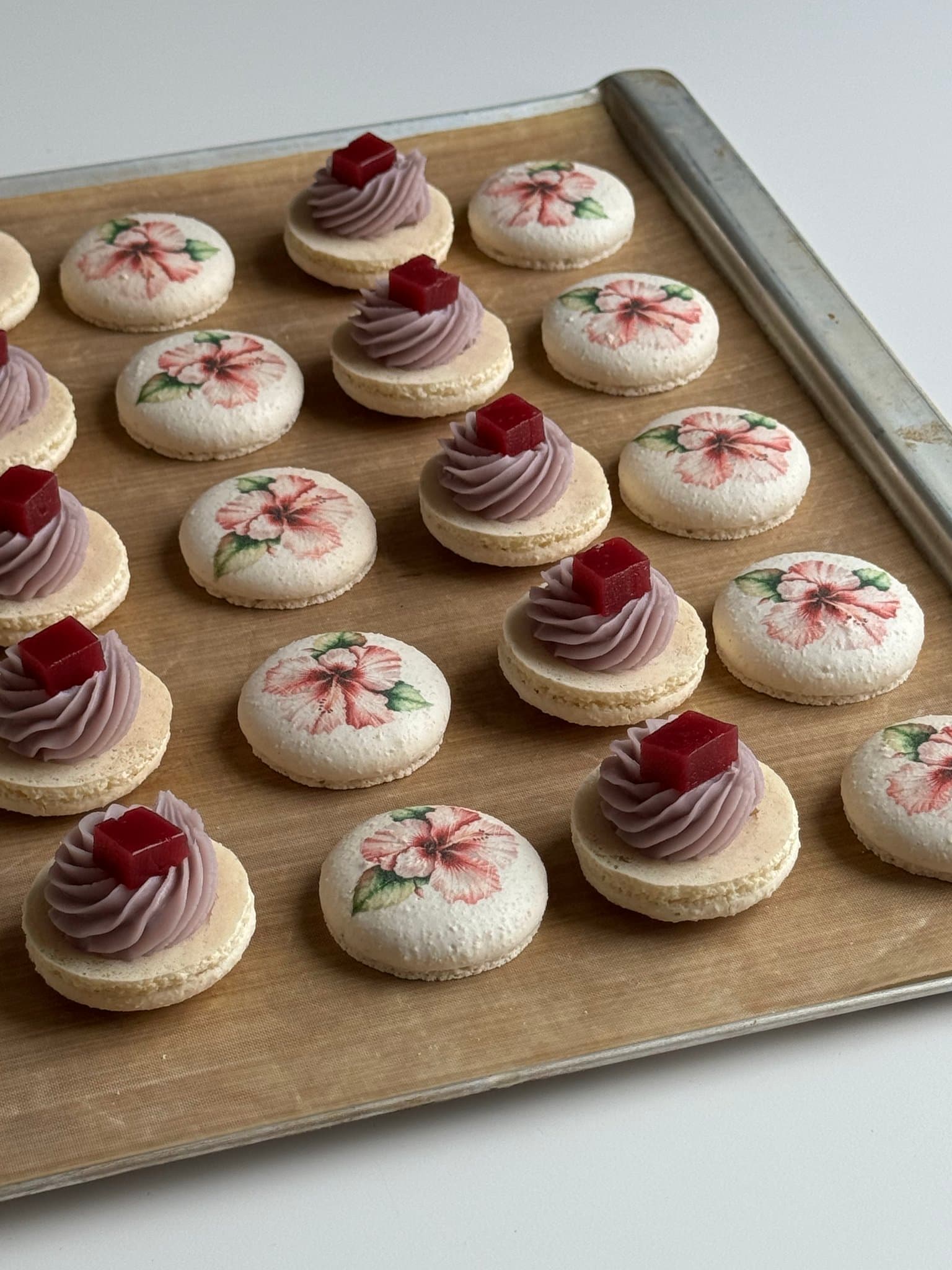 Handmade floral macarons arranged on a bakery tray